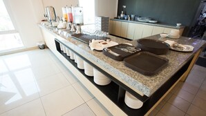 A modern kitchen with a granite countertop, stainless steel appliances, and a large island with various kitchenware and utensils. - Adya Hotel Chenang (Langkawi)