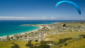 Une ville côtière avec une plage, des maisons et une personne pratiquant le parapente.