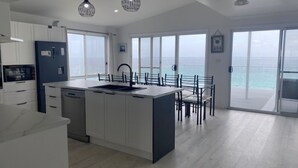 Una cocina moderna con una isla central, ventanas amplias y vistas al mar.