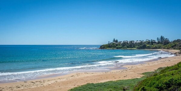 Enjoy a serene coastal setting with a sandy beach and clear blue sea.