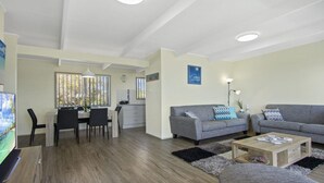Una sala de estar moderna con un sofá gris, una mesa de centro y un comedor con una mesa y sillas.
