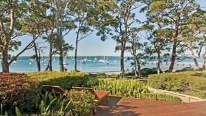 A coastal view with trees, a wooden deck, and sailboats on the water. - Izba - on the foreshore of Callala Bay (Callala Bay)