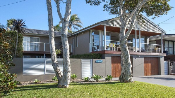 A two-story house with a balcony, a garage, and a well-maintained lawn.
