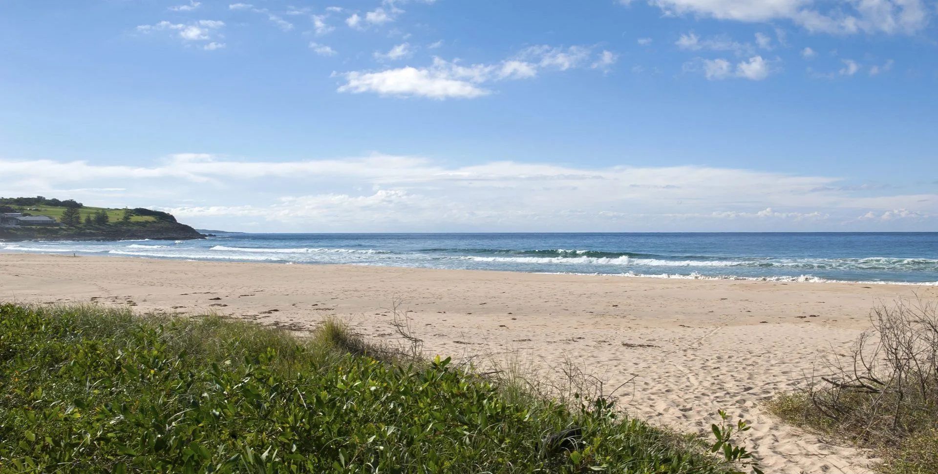 A beach with direct access to the shore, a clear sky, and a calm sea.