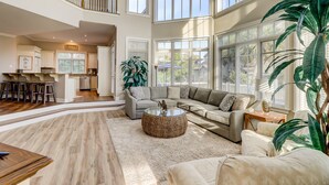 A spacious living area with a large sectional sofa, a coffee table, and a dining area with bar stools. - 2nd Row luxury home with pool, tiki bar, private beach boardwalk- 30 Knotts Way (Hilton Head Island)