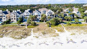 A beachfront property with multiple houses, a sandy beach, and a clear view of the ocean. - 2nd Row luxury home with pool, tiki bar, private beach boardwalk- 30 Knotts Way (Hilton Head Island)
