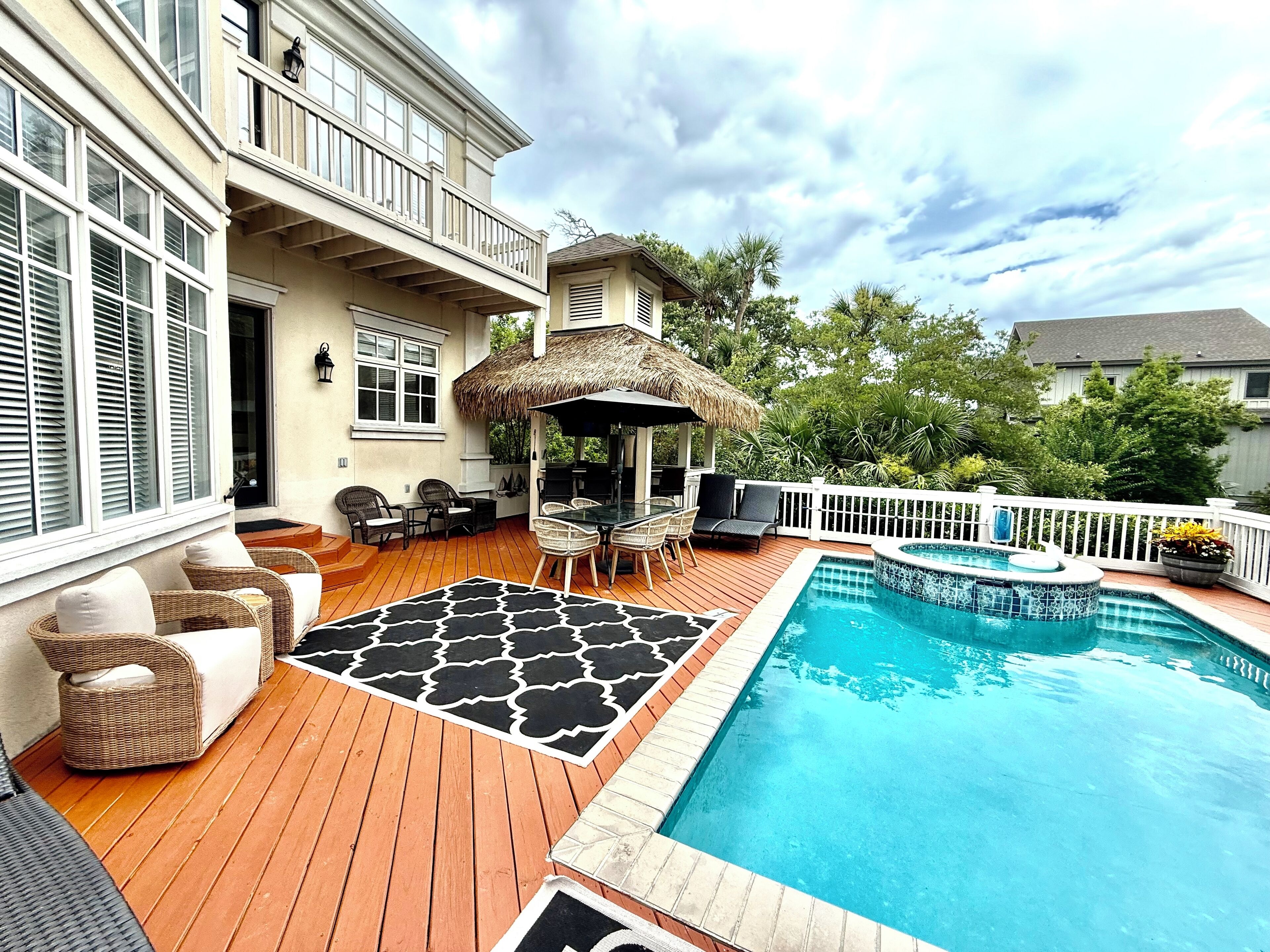 A backyard with a pool, outdoor furniture, and a covered seating area.