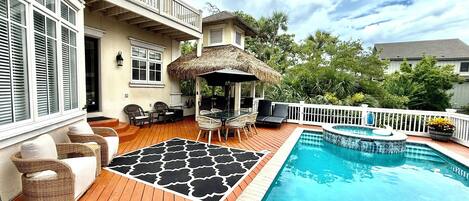 A backyard with a pool, outdoor furniture, and a covered seating area.
