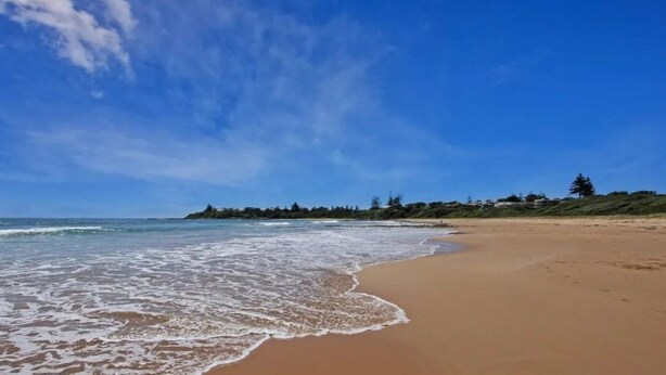 A beach with a clear sky and gentle waves. - Time To Unwind – cute beach house (Culburra Beach)