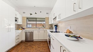 Enjoy cooking in this well-equipped kitchen with sleek cabinetry, a sink, and a stainless steel dishwasher.