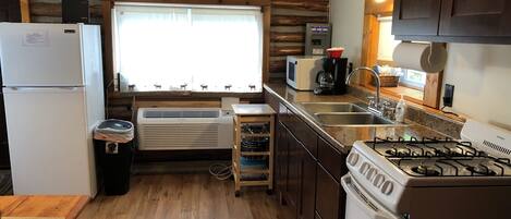 A compact kitchen with a refrigerator, microwave, stove, and sink.