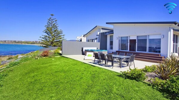 A modern house with a pool, a patio, and a view of the sea.