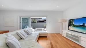 A modern living room with a sofa, a TV, and a sliding glass door leading to an outdoor area.