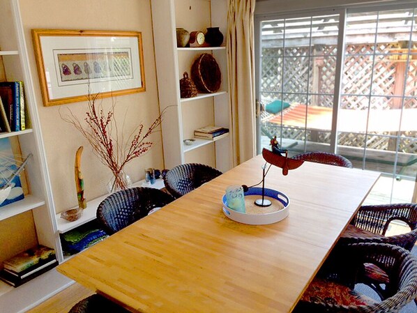 A dining area with a wooden table, wicker chairs, a decorative bowl, and a bookshelf with various items. - 2 blocks to the beach and pet friendly.. Memories are Made Here (Union Pier)