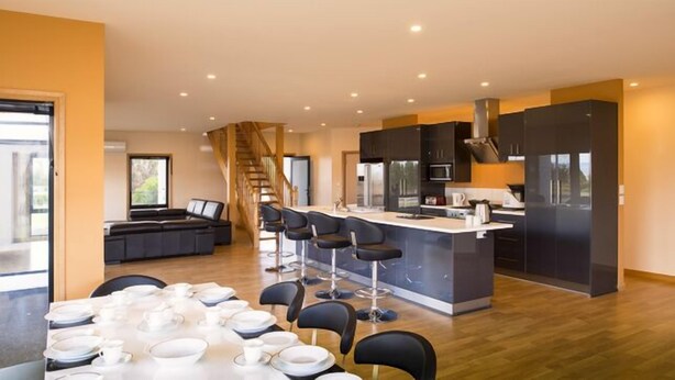 Een moderne keuken met een centraal eiland, barkrukken en een eethoek gedekt voor een maaltijd.