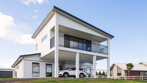 Een modern huis met twee verdiepingen, een overdekte autocarport en een balkon.