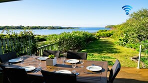 Un espacio para comer al aire libre con vistas al mar, terraza de madera y símbolo de Wi-Fi.