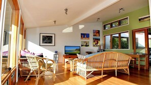 Un salón amplio con un ventanal grande, una televisión y una mesa de comedor con sillas.