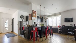 Een moderne keuken met een centraal eiland, barstoelen en een eethoek.