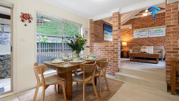 A dining area with a brick wall, a table set for four, and a view of the outdoors.