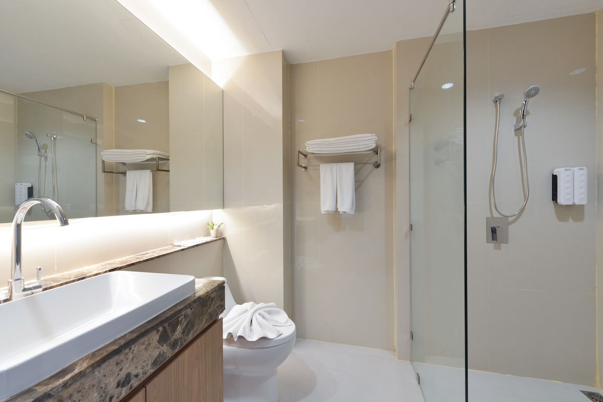 Un baño moderno con cabina de ducha de vidrio, un lavamanos con encimera de mármol y un inodoro.