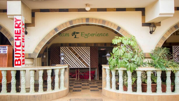 An entrance with a sign for 'Butchers' and 'Room Experience' above an arched doorway. - Heritage Bliss Hotel (Kitui)