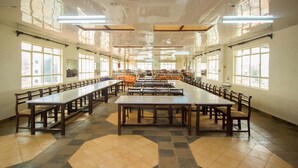 A large, well-lit room with long tables and chairs arranged for dining. - Heritage Bliss Hotel (Kitui)
