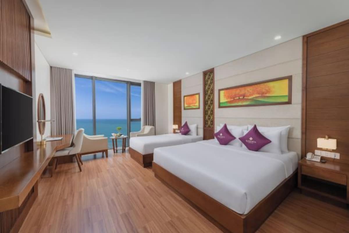Une chambre d’hôtel avec deux lits, une télévision, un bureau et vue sur la mer.