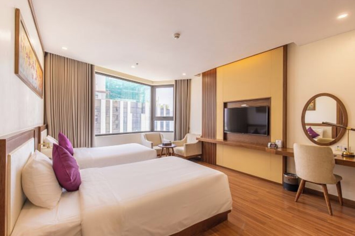 A hotel room with two beds, a TV, a desk, and a chair.