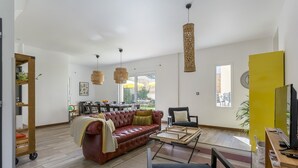Ein geräumiges Wohnzimmer mit einer Ledersofa, einer Essecke mit Tisch und Stühlen, und einer leuchtend gelben Akzentwand.
