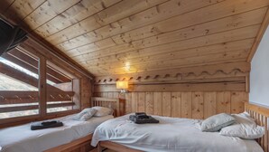 Ein Zimmer einer Holzhütte mit zwei Betten, einem Fenster mit Jalousien und einer Wandleuchte.