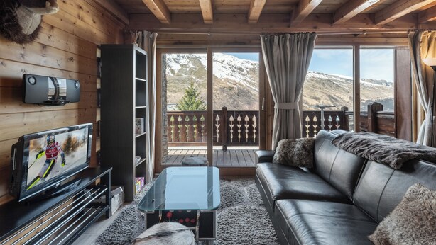 Ein gemütliches Zimmer mit Ledersofa, Fernseher und Holzboden.