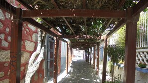 A covered walkway with stone walls and wooden beams, leading to a building with a gated entrance. - SPACIOUS HOUSE IN THE FIELD: Ada´s House 2 (Santa Brígida)