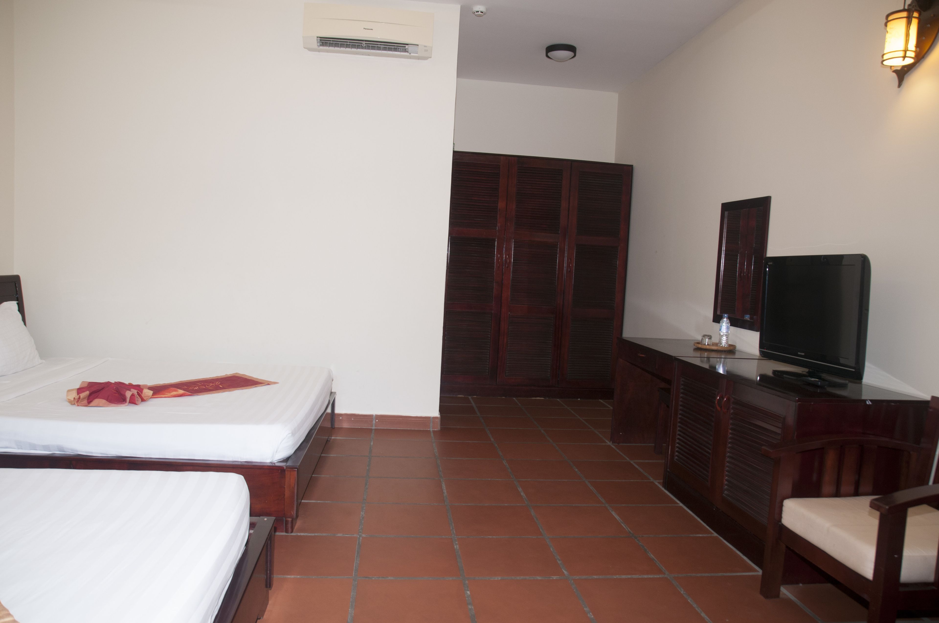 Ein Hotelzimmer mit Bett, Fernseher, Kleiderschrank und Schreibtisch.