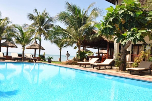 Una piscina al aire libre, sombrillas, sillones reclinables de piscina