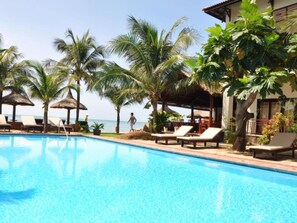 A clear blue pool with lounge chairs and palm trees. - Jardin Des Thes Resort (Mui Ne)