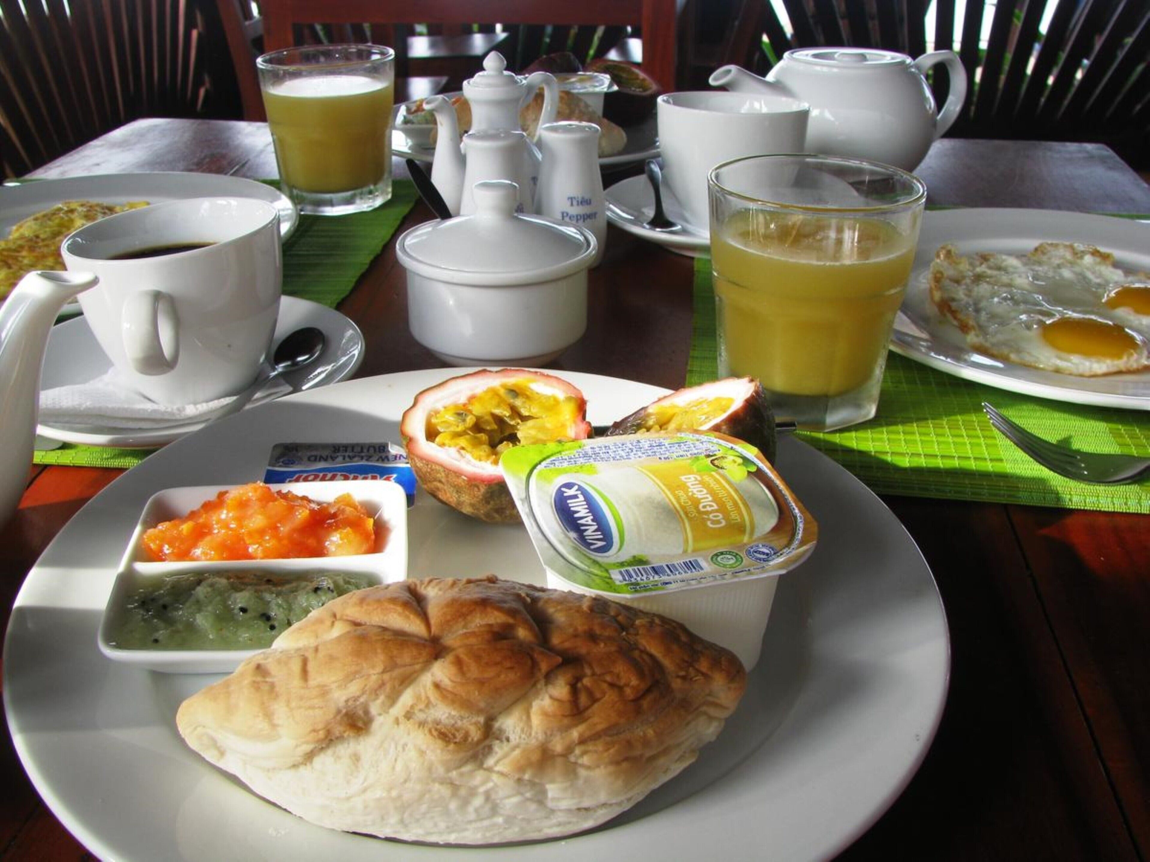 A breakfast setting with a plate of food, including eggs, toast, and yogurt, along with cups of coffee and tea.