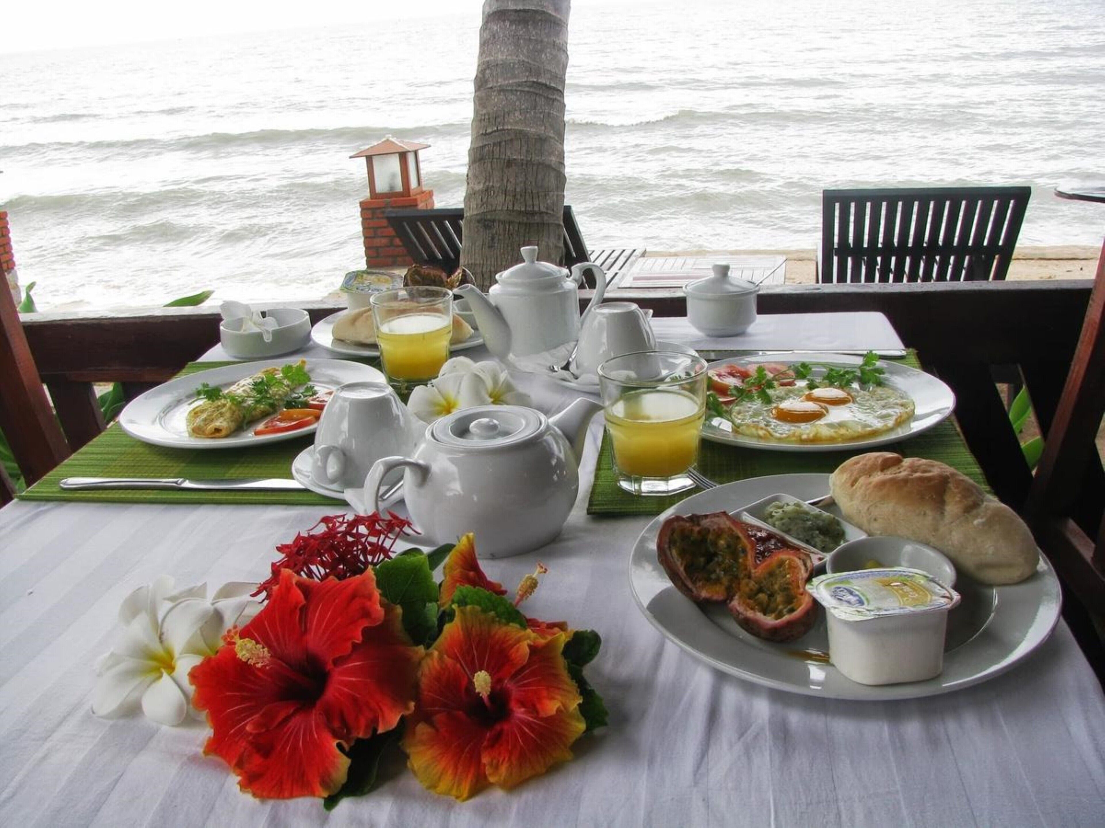 A breakfast setup with a table, plates, and a view of the ocean.
