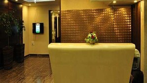 Zona de recepción con mostrador, pantalla de televisión y cartel que dice 'Recepción'.