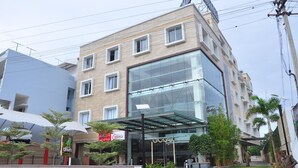 Un hotel de varios pisos con fachada de vidrio, mobiliario exterior y un jardín ajardinado.