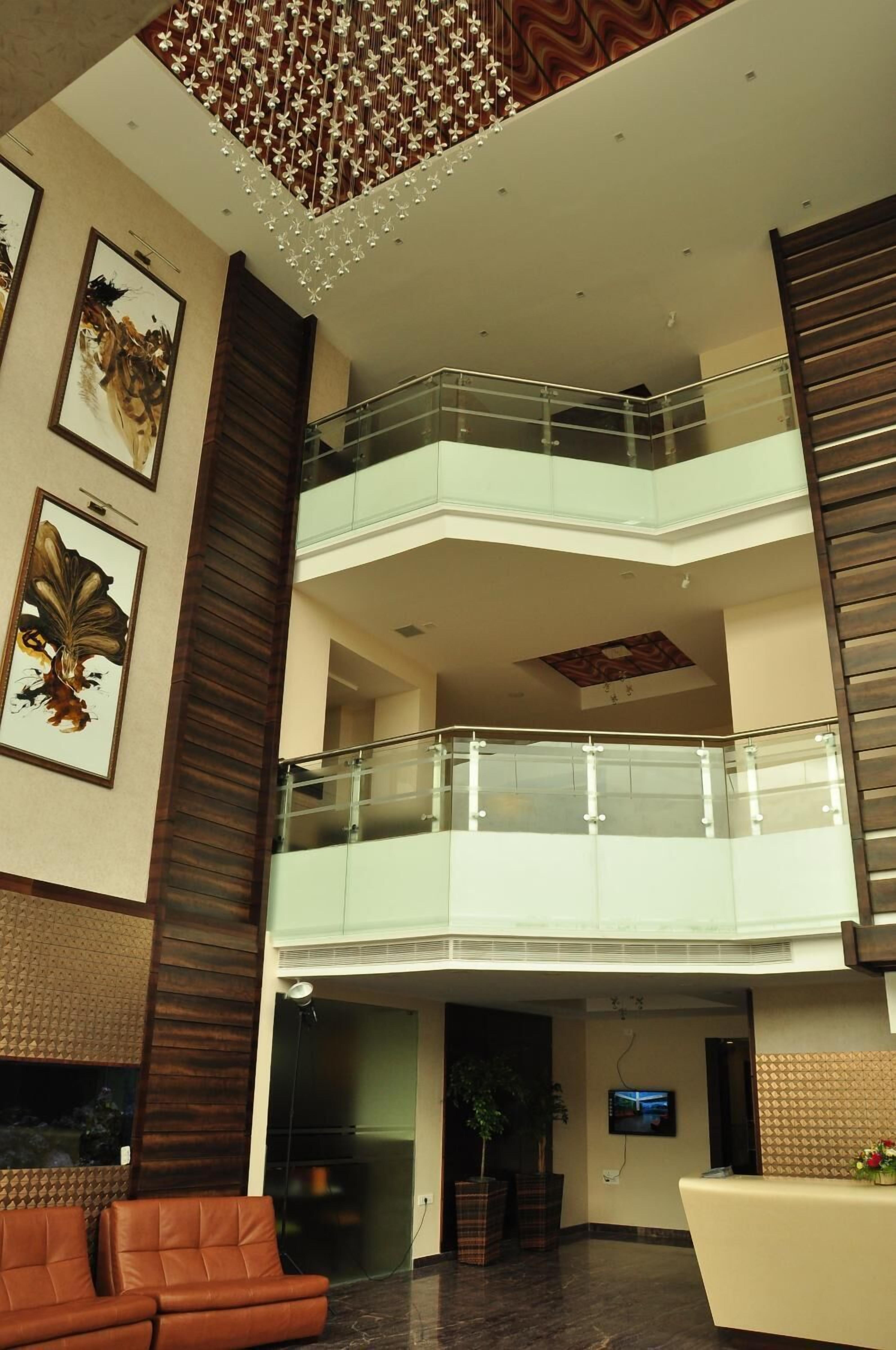 A spacious lobby with a high ceiling, a glass railing balcony, and artwork on the walls.
