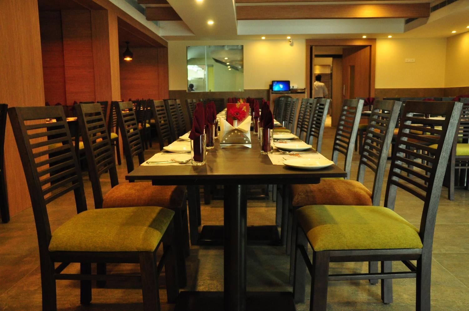 A dining area with a long table set for multiple people, surrounded by chairs with cushioned seats.