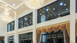 A hotel interior with large windows, chandeliers, and a decorative drape. - Pura Nakhon Hotel (Nakhon Si Thammarat)
