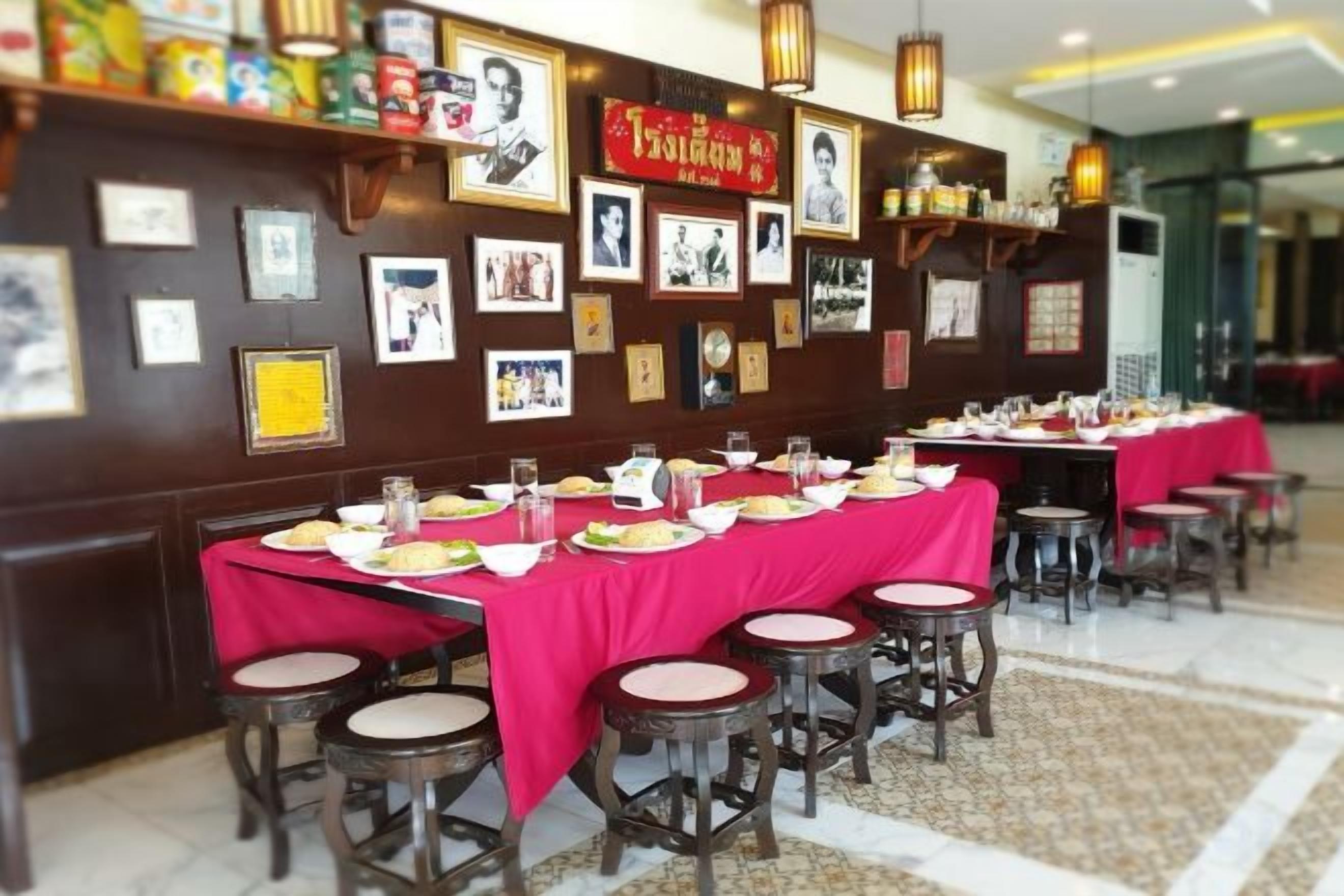 Un restaurante con mesas dispuestas para comer, una pared decorada con cuadros enmarcados y un mantel rojo.