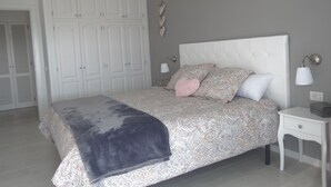 Un dormitorio con cama, mesita de noche, armario y una lámpara fijada a la pared.
