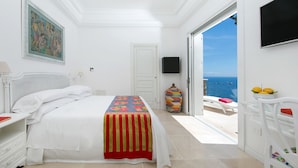 A bedroom with a bed, a TV, a painting, and a view of the sea. - AMORE RENTALS - Villa Ibiscus with Infinity Pool, Direct Sea Access, Sea View, Parking and Breakfast (Nerano)