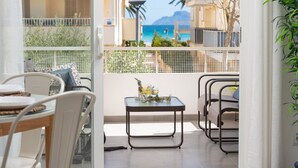 Un balcon avec une table dressée pour deux personnes, une chaise et une vue sur la mer.