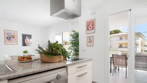 Une cuisine moderne dotée d’un plan de travail en granit, d’un lave-vaisselle encastré et d’un coin repas avec une table et des chaises.