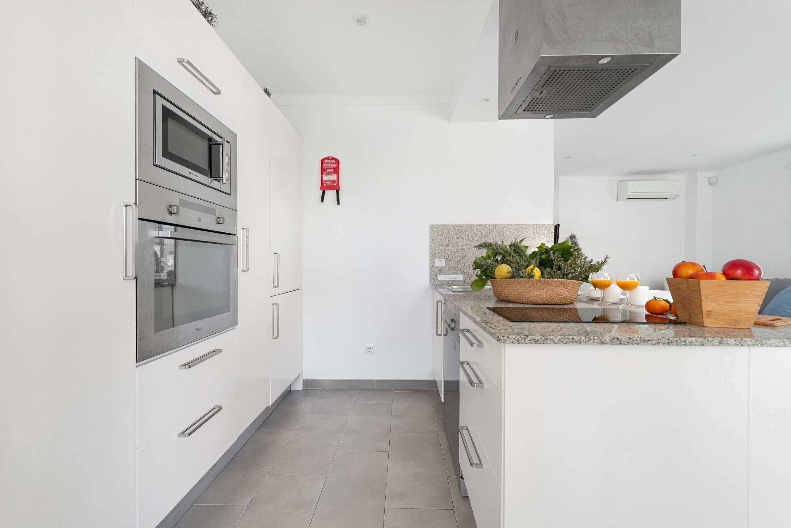 A modern kitchen with stainless steel appliances, white cabinetry, and a granite countertop.