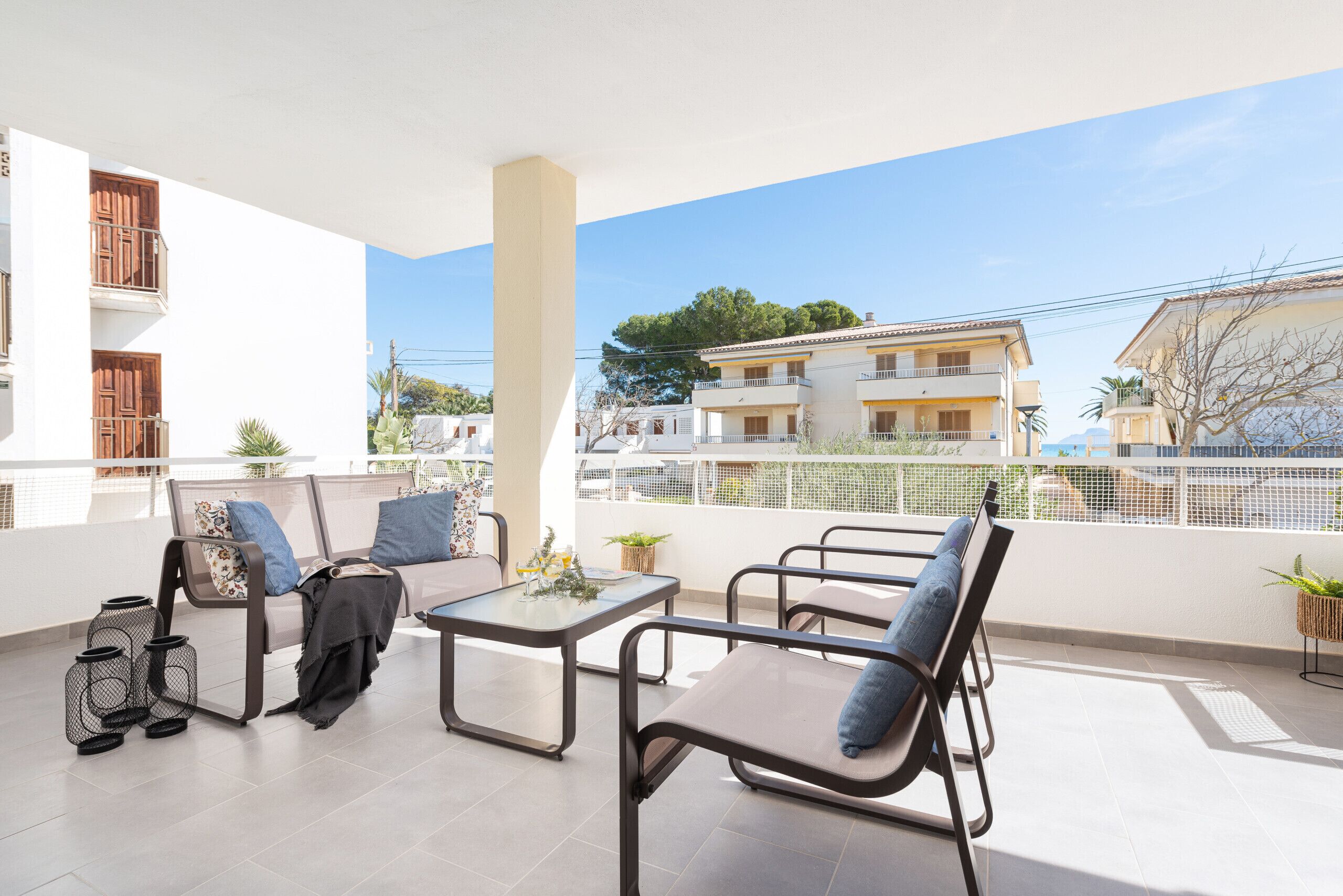 A balcony with a table and chairs, a sofa, and a potted plant.